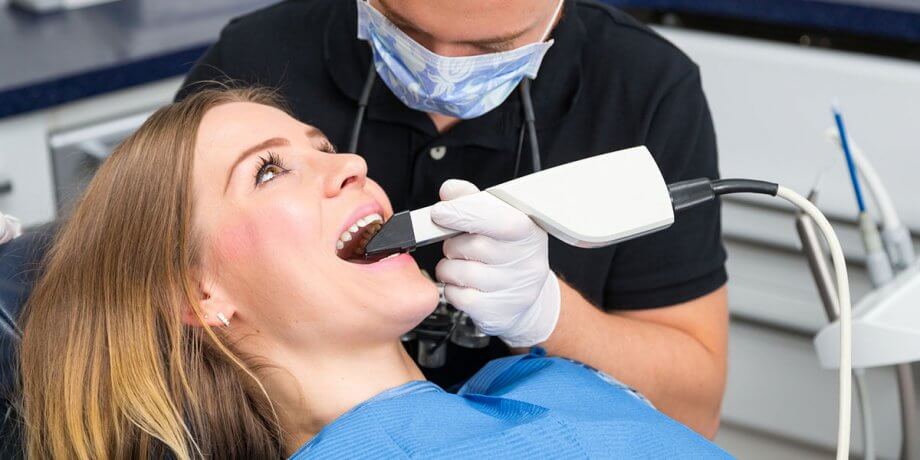 dentist using digital scanner on female patient's mouth