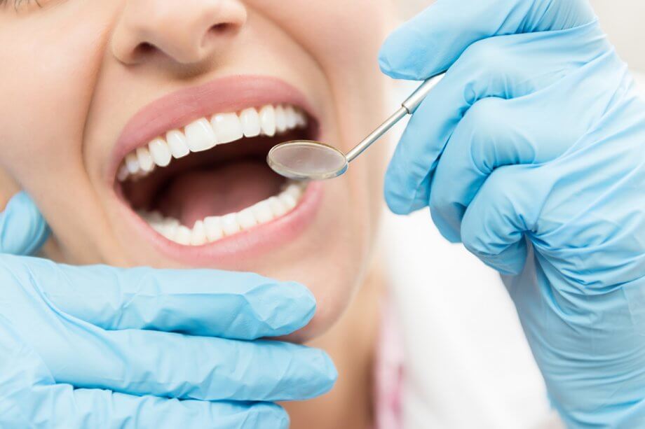 close-up of person's mouth with dental mirror