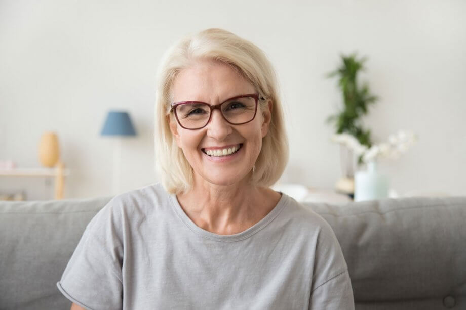 older blonde woman wearing red glasses, smiling