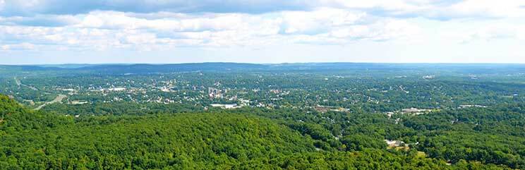 panoramic view of town, rolling hills and cloudy blue sky