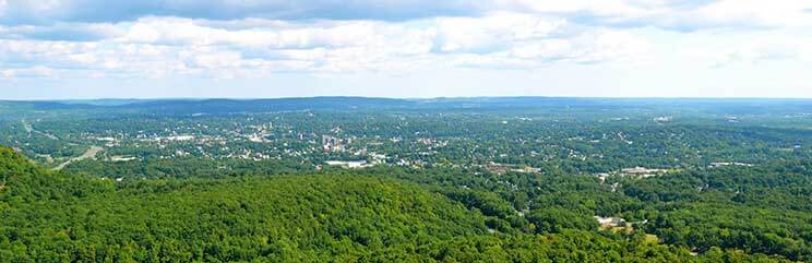 panoramic view of town, rolling hills and cloudy blue sky